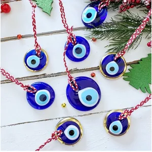 Dettaglio di ciondoli Evil Eye in vetro blu con corde rosse e bianche su sfondo festivo