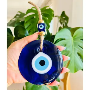 Détail d'un grand pendentif œil porte-bonheur en verre bleu avec perles dorées en main