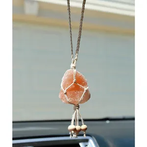 Detail view of handmade macrame wrap with pink salt crystal hanging in a car interior