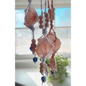 Detailed handmade cotton rope weave holding a pink Himalayan salt stone and evil eye bead
