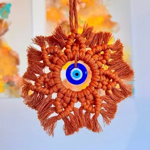 Macro view of rust red handmade macrame star wall decor with blue glass evil eye