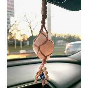 Macro detail of hand-woven cotton net holding a raw pink crystal and evil eye charm