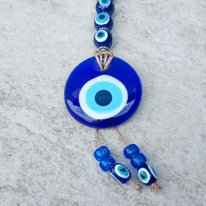 Decorazione Evil Eye in vetro blu con perline e corda naturale su sfondo in pietra