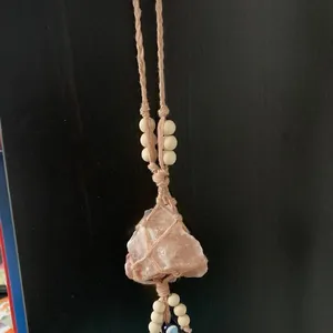 Detailed handmade woven net holding a raw pink Himalayan salt crystal with wooden beads