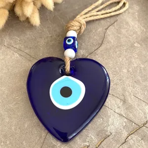 Macro detail of a heart-shaped blue evil eye glass pendant with rustic hemp rope and beads