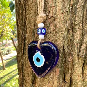 Macro shot of blue heart-shaped evil eye glass wall hanging on natural tree bark