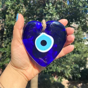 Detail of a large heart-shaped blue glass Nazar evil eye wall hanging with a jute rope