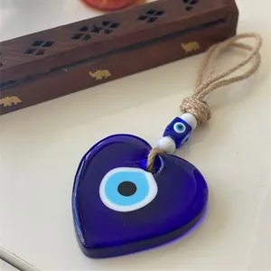 Detail of blue glass heart evil eye pendant with rustic jute rope and decorative beads