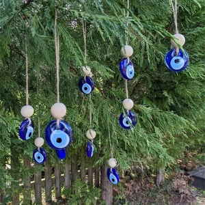 Blue glass evil eye ornaments with wooden beads hanging on green pine tree branches