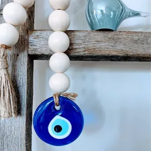 Detail of wooden beads garland with glass Evil Eye charm and rustic jute tassel hanging