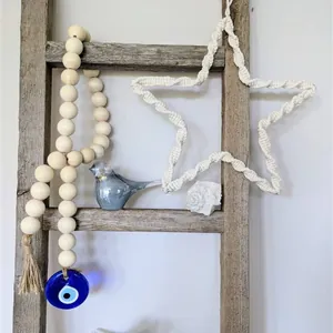 Detail of wooden bead garland featuring blue evil eye glass pendant and jute tassel