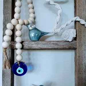 Detail of wooden bead garland with Evil Eye charm and glass bird on a rustic wooden ladder