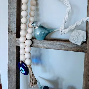 Detail of wooden bead garland with Evil Eye charm and blue glass bird decor