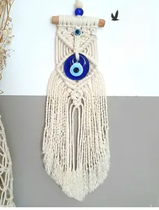 Detail of handmade macrame wall hanging with evil eye bead and natural cotton fringes