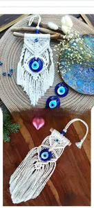 Detail of handmade macrame evil eye wall hanging with blue glass charm and cotton tassels