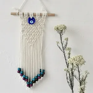 Detail of handmade macrame evil eye wall hanging with blue glass pendant and beads