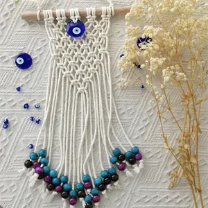 Detailed close-up of Bohemian woven macrame wall hanging with evil eye beads and fringes
