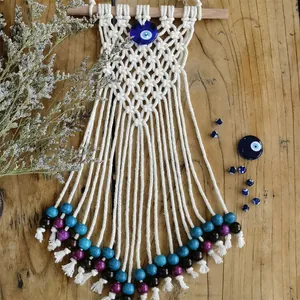 Close-up of handmade Bohemian evil eye tapestry with colorful beads and white tassels