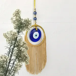 Détail d'une suspension murale Nazar faite main avec des glands dorés et des perles bleues