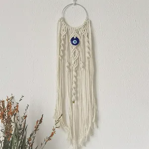 Detailed view of handmade macrame evil eye wall hanging with long cotton tassels