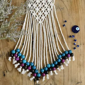 Detail of handcrafted macrame wall hanging with evil eye beads on wood background