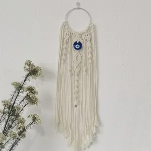 Detailed view of woven macrame wall hanging featuring a blue evil eye bead and fringes