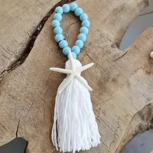 Detail of wooden beads, resin starfish, and white cotton tassel on a wood background