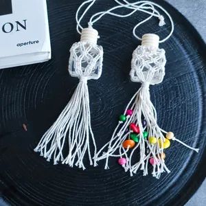 Detail of macrame car perfume bottles with wood beads and handmade tassels on a black tray