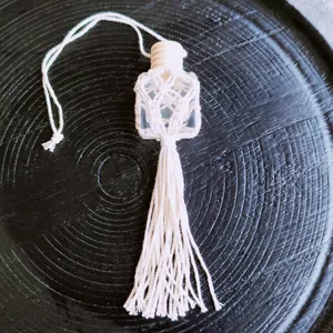 Detail of hand-woven cotton macrame cover and fringe for a glass car perfume bottle