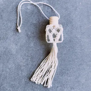 Detail of hand-woven macrame perfume bottle with wooden lid and tassels for car decor