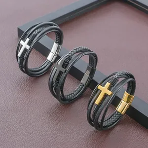 Détail de bracelets multicouches en cuir avec croix en métal argenté, doré et noir