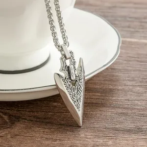 Detailopname van retro zilveren pijl hanger aan een botketting op een houten tafel