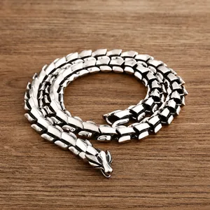 Macro shot of silver keel chain with detailed dragon head clasp on wooden background