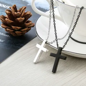 Detail van zilveren en zwarte kruis kettingen op een houten blad in lifestyle setting