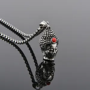 Close-up of vintage stainless steel Buddha pendant with red bead and box chain detail