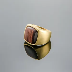 Vista detallada de un anillo de sello dorado con piedra de ojo de tigre cuadrada y mate