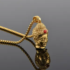 Macro view of golden Buddha pendant with red bead accent and matching box chain