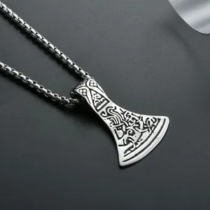 Close-up of Nordic Viking axe pendant with intricate engravings on a black surface