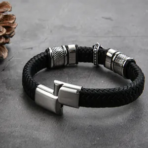 Détail du bracelet en cuir tressé noir avec fermoir en acier sur surface en pierre