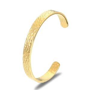 Detailansicht eines goldenen C-förmigen Armreifs mit einer einzigartigen Hammerschlag-Textur