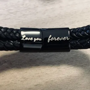 Dettaglio macro del bracciale in pelle intrecciata nera con incisione Love You Forever