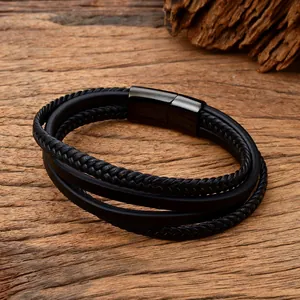 Detail of multi-layer black braided leather bracelet with black magnetic clasp on wood