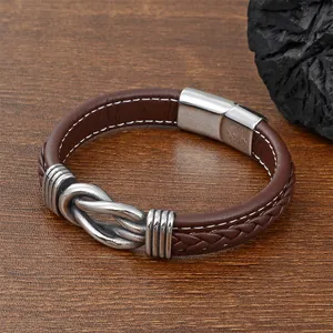 Detail of dark brown braided leather bracelet with silver magnetic clasp on wood