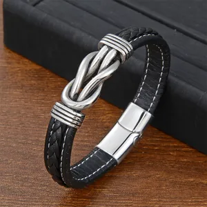 Macro view of black braided leather bracelet with white stitching and silver metal knot