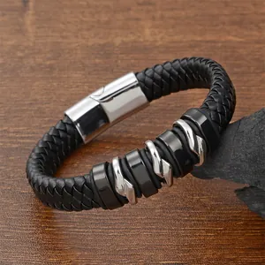 Men's braided black leather bracelet with silver steel rings on a dark stone background