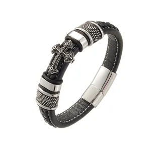 Detail of black woven leather bracelet with vintage silver cross and magnetic metal clasp
