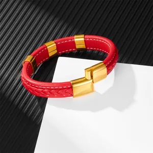 Red braided leather bracelet with polished gold metal clasp on a geometric display