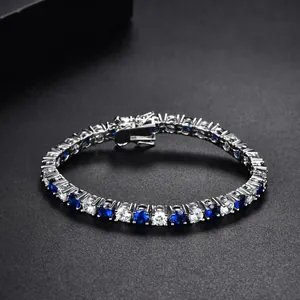 Silver tennis bracelet with alternating blue and clear zircon stones on black background