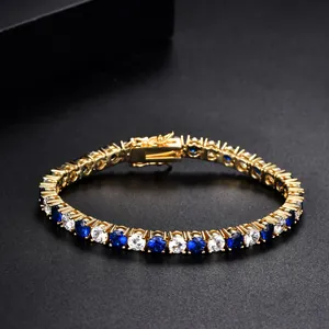 Golden tennis bracelet with navy blue and clear zircons shown on a black background