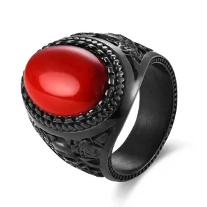 Detail of a vintage black steel ring featuring a red oval stone and rose floral relief